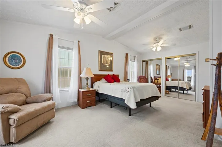 Bedroom featuring a textured ceiling, lofted ceiling with beams, carpet, and ceiling fan