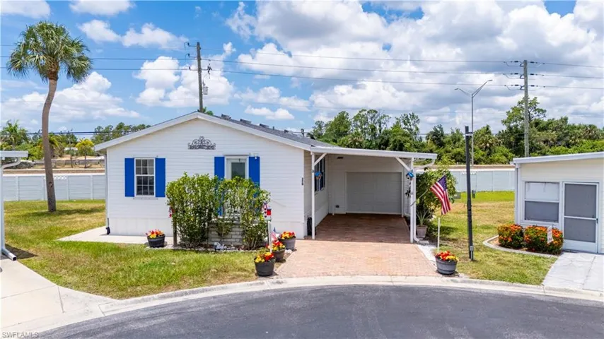 View of front of home with a garage, a carport, and a front yard