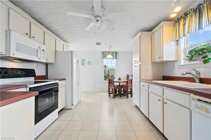 Kitchen featuring plenty of natural light, sink, decorative light fixtures, and white appliances