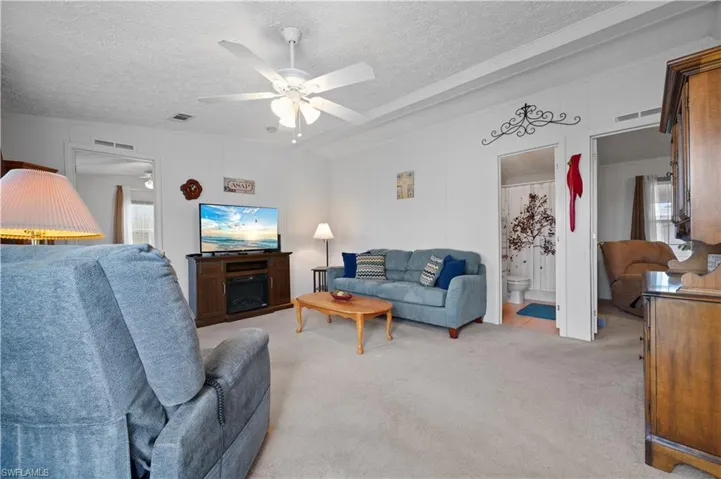 Living room featuring a textured ceiling, carpet floors, and ceiling fan