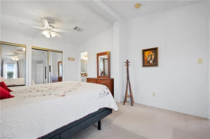 Bedroom with a textured ceiling, two closets, lofted ceiling, carpet floors, and ceiling fan