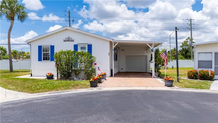 View of front of house with a garage, a carport, and a front lawn