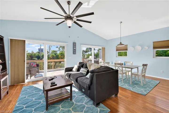 Living area featuring light wood-style floors, ceiling fan, and lofted ceiling