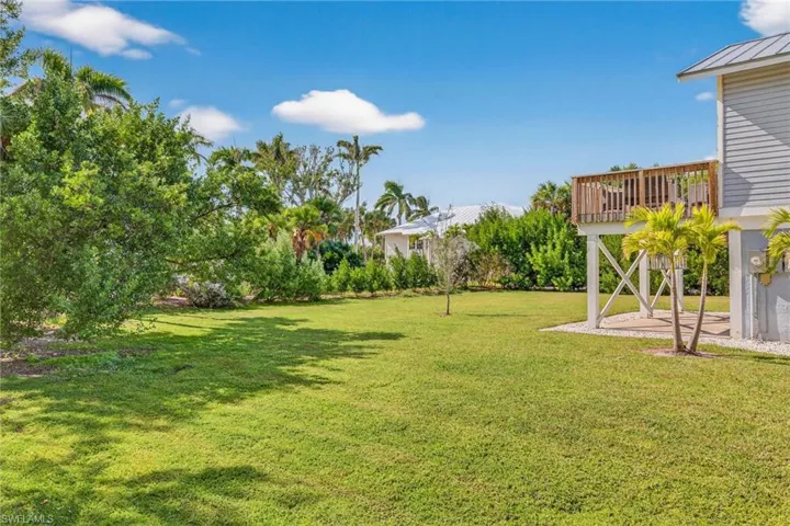 View of green lawn featuring a patio and a deck