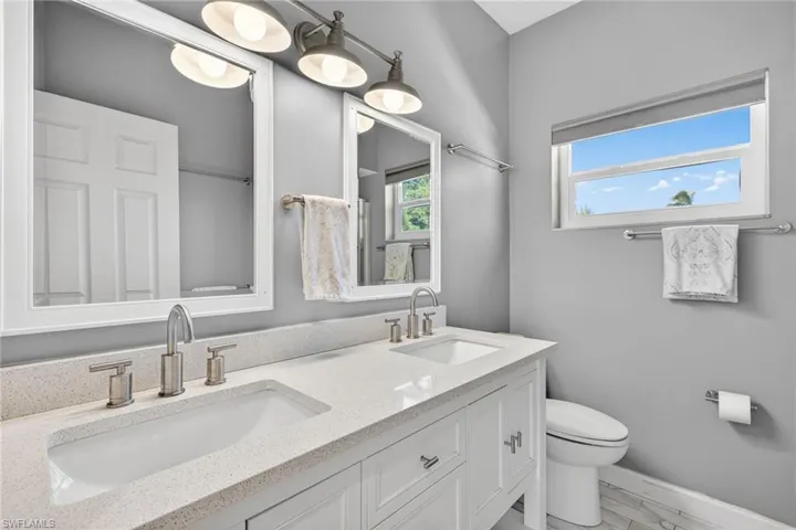 Bathroom with double vanity and light marble finish floors