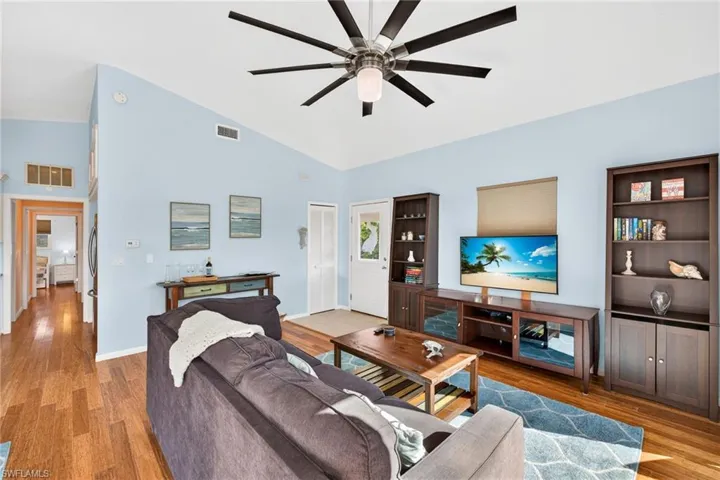 Living area featuring light wood-style floors, a ceiling fan, and high vaulted ceiling