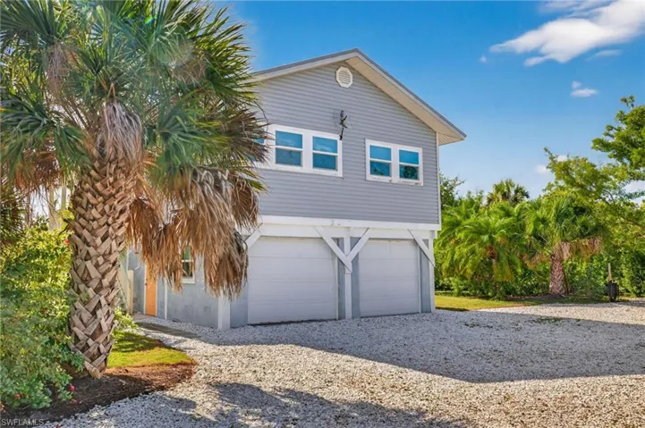 View of side of home with gravel driveway and an attached garage