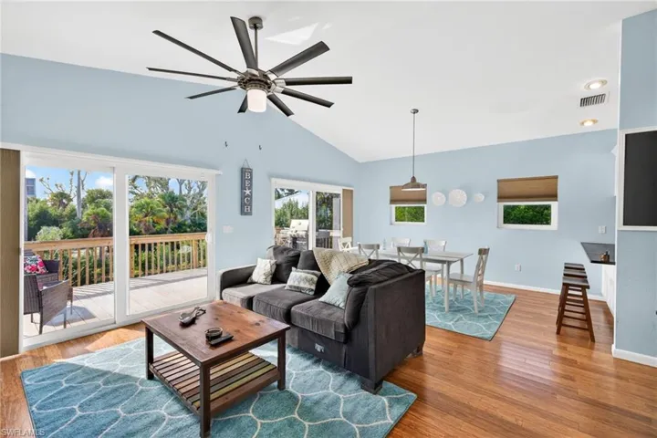 Living room featuring light wood finished floors, plenty of natural light, lofted ceiling, and ceiling fan