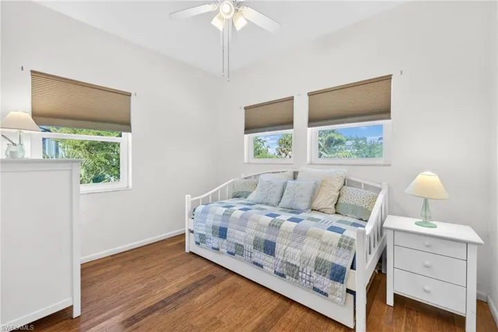 Bedroom with multiple windows, dark wood-style flooring, and ceiling fan