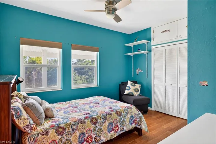 Bedroom with dark wood-style floors, a closet, and a ceiling fan