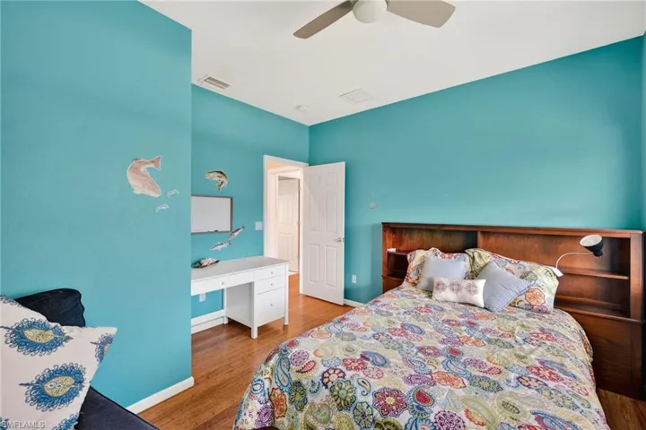 Bedroom with ceiling fan, light wood-style floors, and a desk
