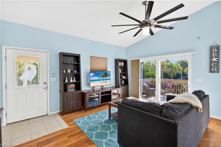 Living room with plenty of natural light, light wood-type flooring, lofted ceiling, and a ceiling fan