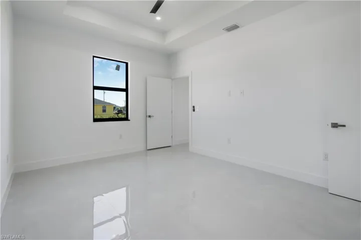 Empty room with a tray ceiling, visible vents, baseboards, and recessed lighting