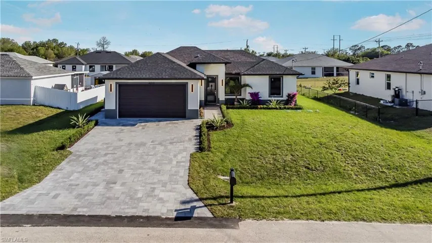 Ranch-style house featuring stucco siding, a front lawn, driveway, fence, and an attached garage