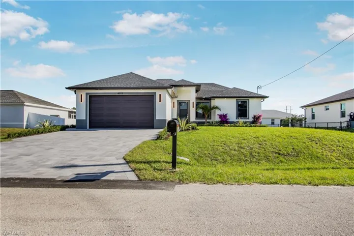 Prairie-style house featuring fence, driveway, stucco siding, a front lawn, and a garage