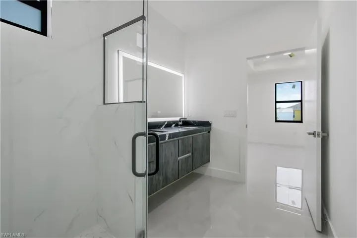 Bathroom featuring a sink, a marble finish shower, baseboards, and double vanity