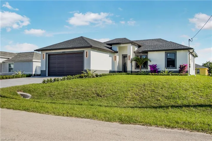 Prairie-style home with concrete driveway, an attached garage, a front yard, and stucco siding