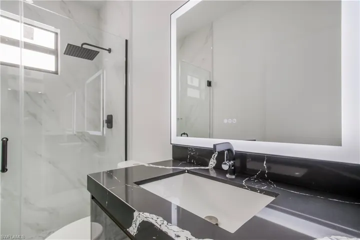 Bathroom featuring a marble finish shower, toilet, and vanity