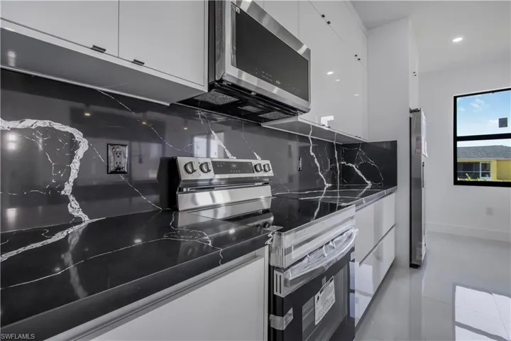 Kitchen with white cabinets, modern cabinets, tasteful backsplash, and stainless steel appliances