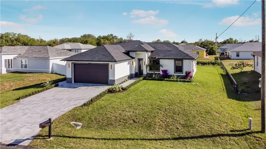 Ranch-style home featuring stucco siding, a front lawn, decorative driveway, and a garage