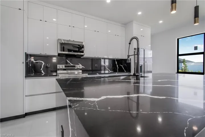 Kitchen featuring modern cabinets, tasteful backsplash, appliances with stainless steel finishes, and white cabinets