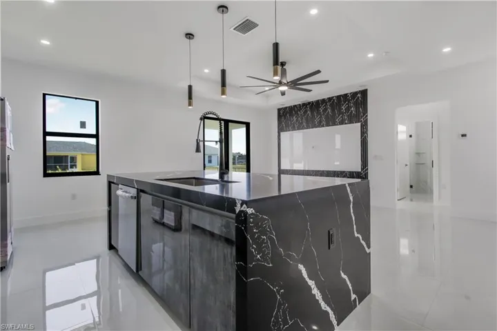 Kitchen featuring plenty of natural light, stainless steel dishwasher, modern cabinets, and a large island with sink