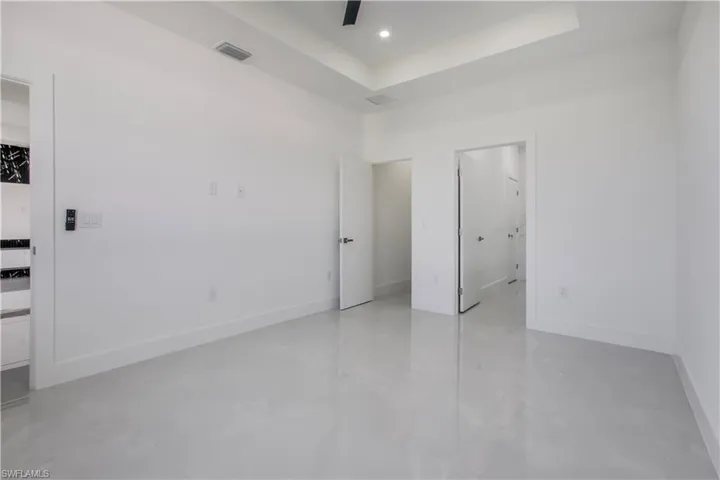 Unfurnished bedroom featuring visible vents, recessed lighting, a tray ceiling, and baseboards