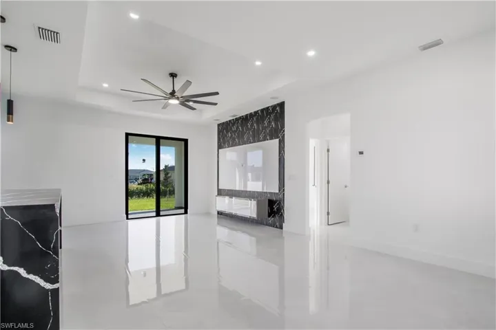 Living room with recessed lighting, a tray ceiling, visible vents, and a ceiling fan