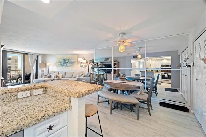 Kitchen with white cabinetry, light hardwood / wood-style floors, decorative light fixtures, a breakfast bar area, and appliances with stainless steel finishes