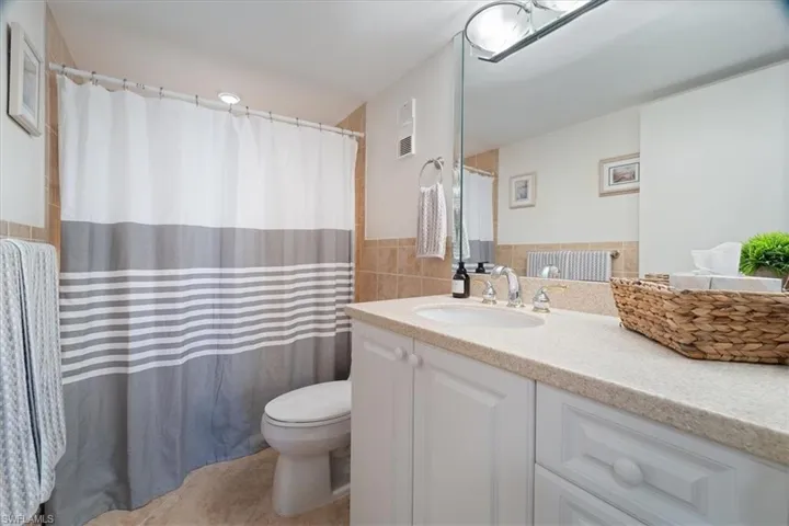 Bathroom with vanity, toilet, and tile walls