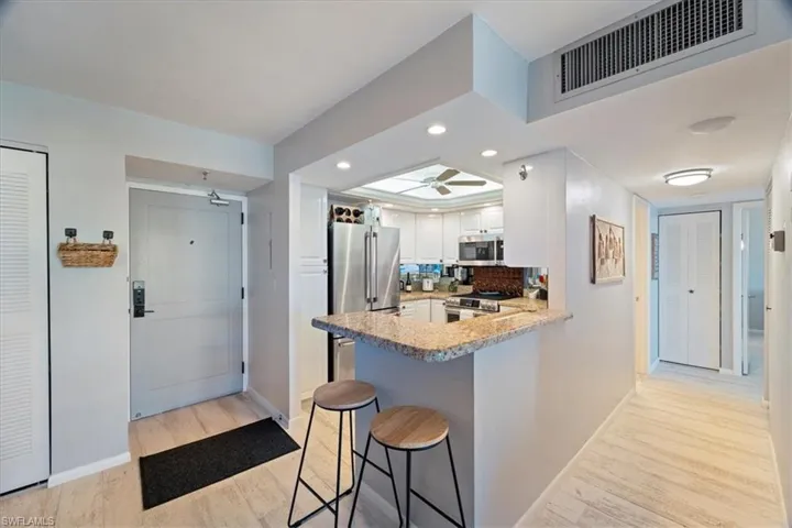 Kitchen with white cabinetry, stainless steel appliances, kitchen peninsula, a breakfast bar area, and light wood-type flooring