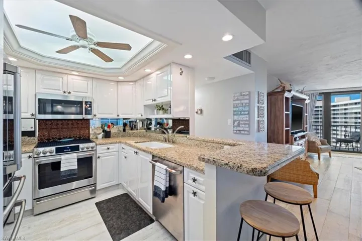 Kitchen with kitchen peninsula, appliances with stainless steel finishes, sink, white cabinetry, and a breakfast bar area