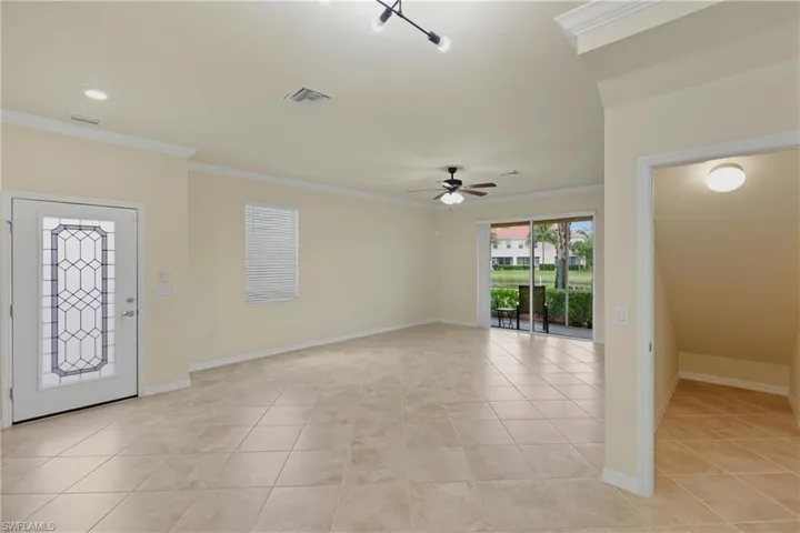 Foyer entrance with ornamental molding, a ceiling fan, and light tile patterned floors