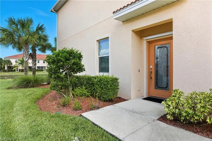Property entrance with a yard and stucco siding