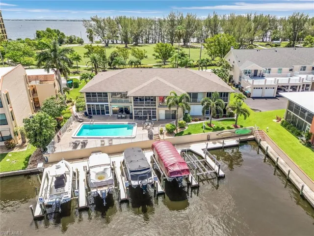 Back of property with a patio area, a water view, and a fenced in pool