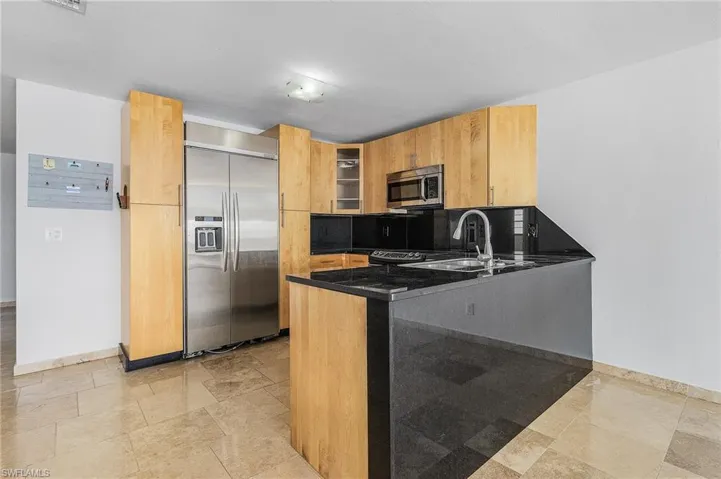 Kitchen featuring tasteful backsplash, light tile flooring, kitchen peninsula, and stainless steel appliances