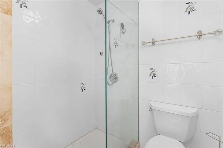 Bathroom with walk in shower, toilet, and tile walls