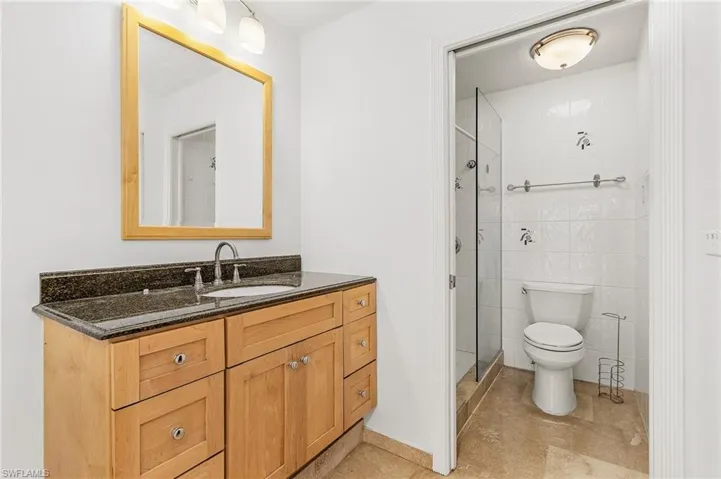 Bathroom with tile walls, toilet, tile flooring, an enclosed shower, and vanity