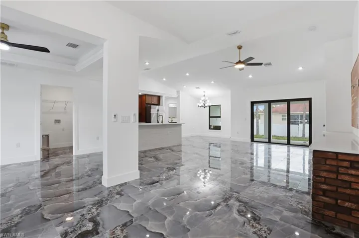 Unfurnished living room featuring a ceiling fan, marble tiled flooring, hanging lights, and lofted ceiling