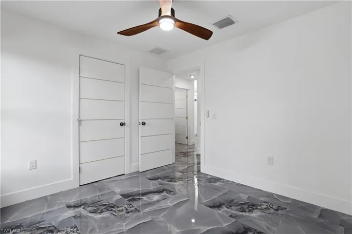 Bedroom with dark marble finish floors and ceiling fan