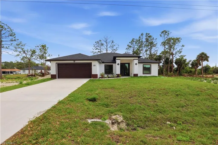 Prairie-style house featuring a front lawn, a garage, concrete driveway, stucco siding, and roof with shingles