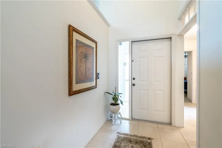 Foyer with light tile patterned flooring and baseboards