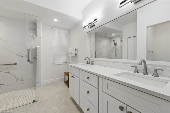 Full bath with double vanity, a marble finish shower, and recessed lighting