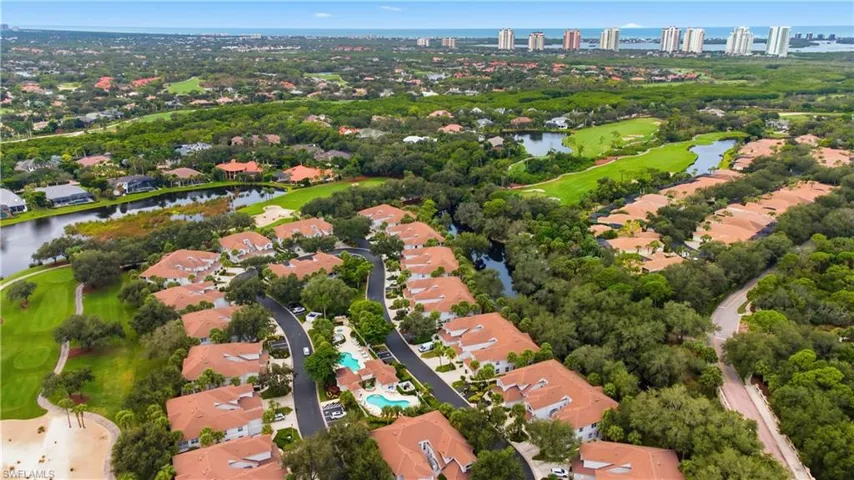 Aerial view of residential area featuring a nearby body of water and a golf course