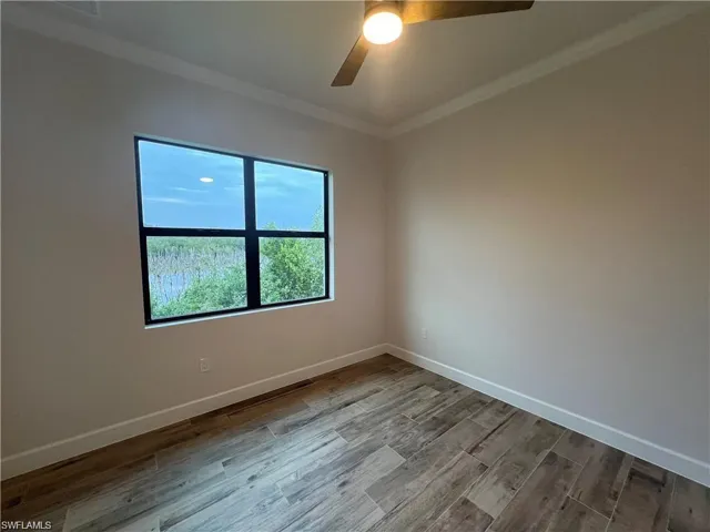 Empty room featuring ceiling fan, hardwood / wood-style flooring, and ornamental molding