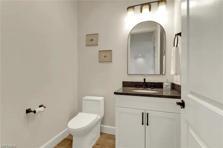 Bathroom with hardwood / wood-style floors, vanity, and toilet