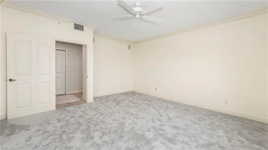 Spare room featuring crown molding, light colored carpet, and a ceiling fan