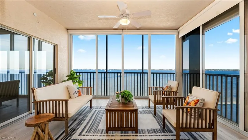 Sunroom featuring a water view, hardwood / wood-style floors, a textured ceiling, and expansive windows