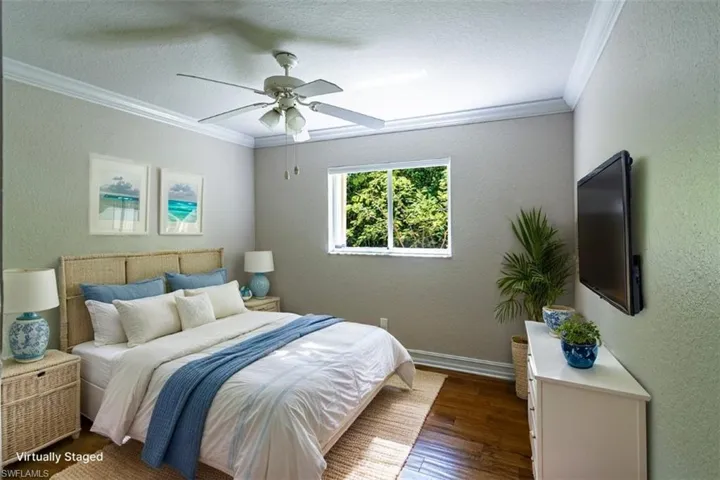 Room featuring dark wood-finish flooring, crown molding, a central ceiling fan with integrated lighting, and a window with an exterior landscape perspective