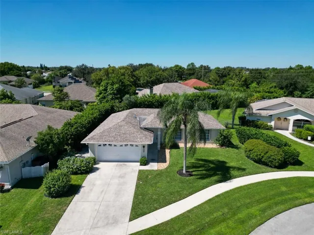 Single-story residence featuring a shingled hip roof, a screened-in rear patio, and an expansive lawn with mature perimeter landscaping